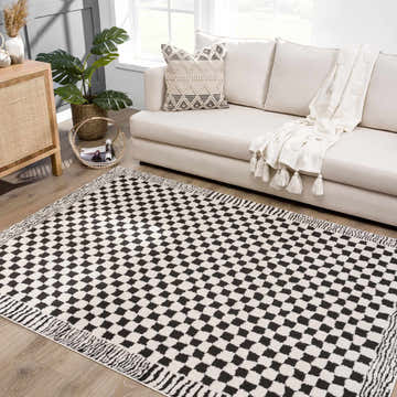 Living room scene with a Leryn Black & White Checkered Area Rug, ivory sofa, wood cabinet, and monstera plant. Roomscene-Rectangle