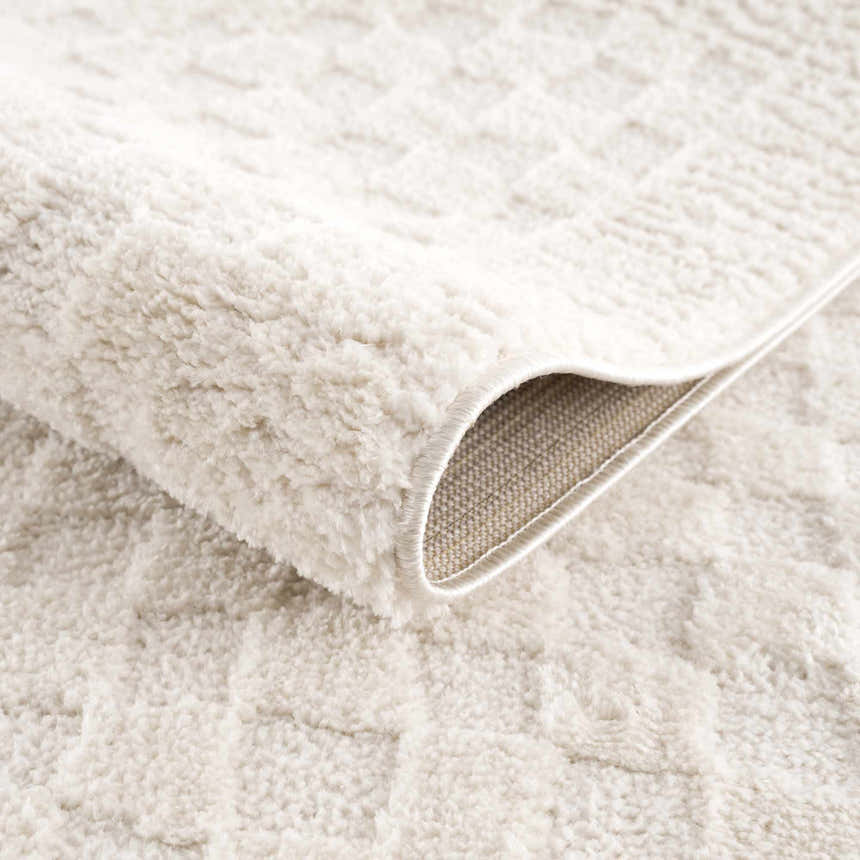 Close up of the plush, ivory Leryn Checkered Area Rug showing its soft texture and geometric pattern. Fold