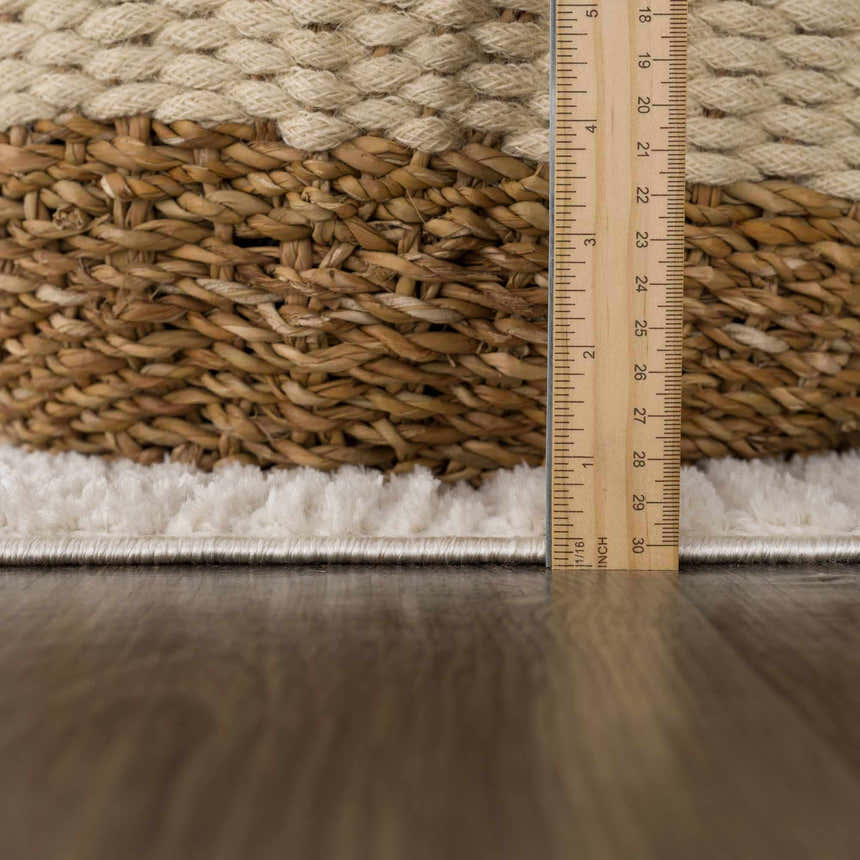 Close-up of the Leryn Ivory Checkered Area Rug showing its ivory pile height and beige woven backing with a ruler for scale. Pile