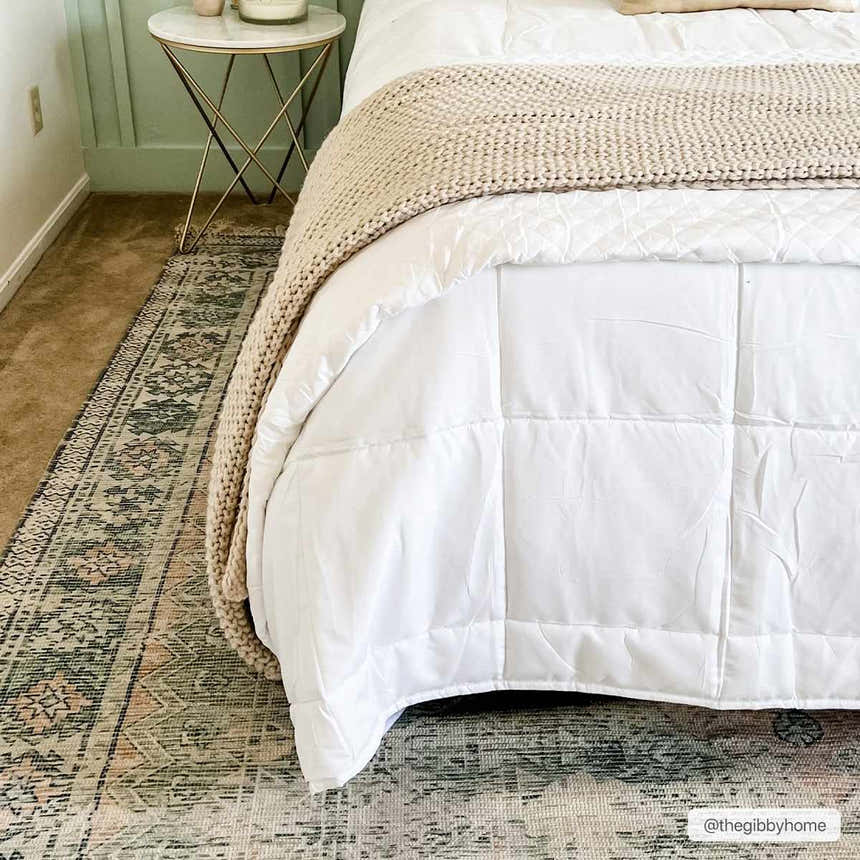 Bedroom scene with a Foraker Sage Green Cotton Rug, white bedding, and gold side table. Roomscene-Rectangle