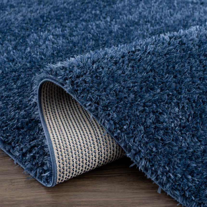 Close-up of the Faina Solid Dark Blue Shag Washable Area Rug showing its plush texture and backing. Fold