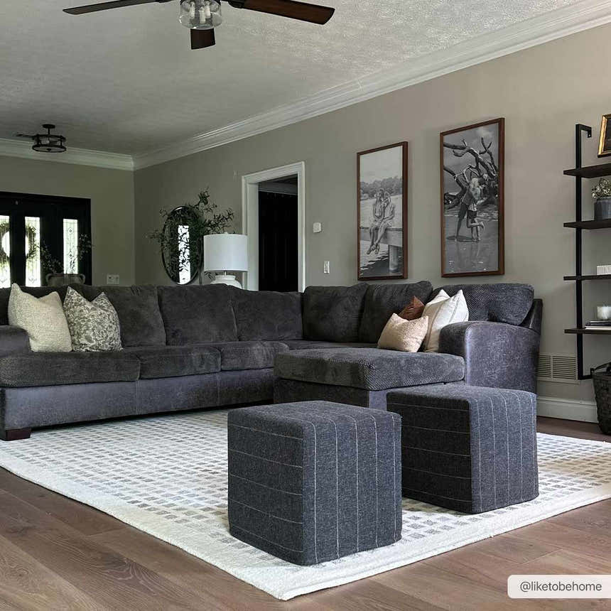 Living room scene with a gray sectional sofa on a beige geometric Harib Area Rug. Two striped ottomans sit on the rug. Roomscene-Rectangle
