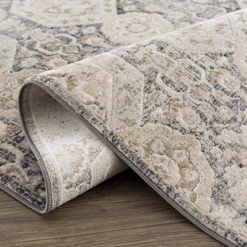 Close-up of the Minoa Area Rug, showcasing its beige, black, charcoal, and gray bohemian-style pattern and machine-woven texture. Fold