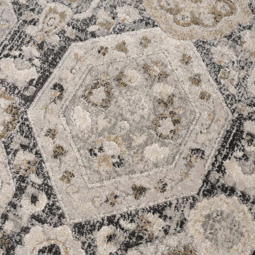 Close-up of the Minoa Area Rug showing a geometric, floral pattern in beige, black, charcoal, gray, mustard, and off-white. Texture