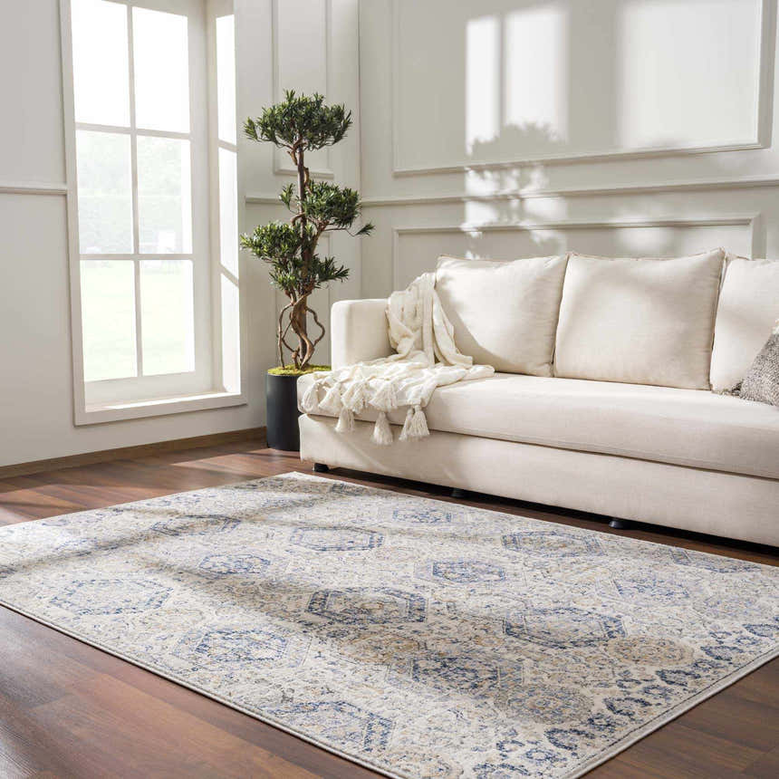 Living room scene with a Parkerfield Cream & Blue Area Rug, beige sofa, wood floors, and bright natural light. Roomscene-Rectangle