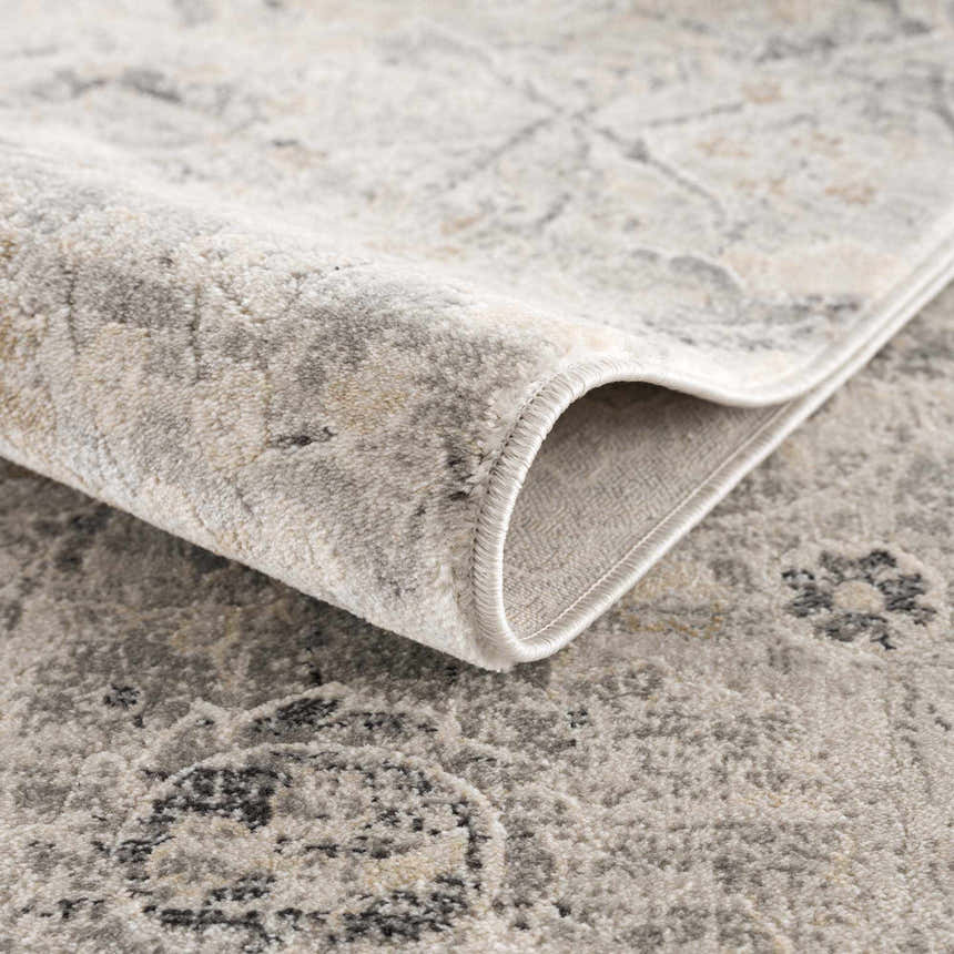 Close up of the Georgiana Area Rug showing its beige, black, and gray traditional pattern and machine woven texture. Fold