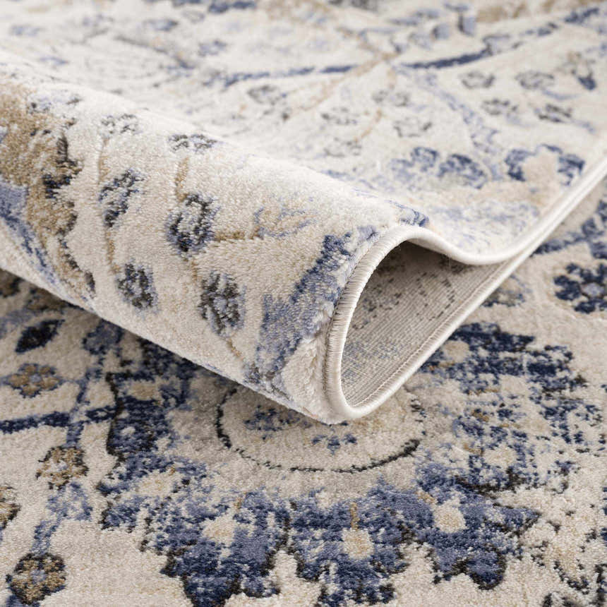 Close-up of the Georgiana Blue & Beige Oushak Rug showing its floral pattern, soft texture, and rolled edge. Fold