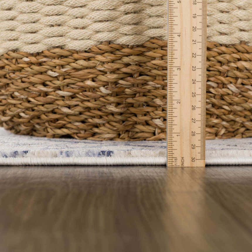 Close-up of the Georgiana Blue & Beige Oushak Rug showing the rug's pile height with a ruler and a basket. Pile