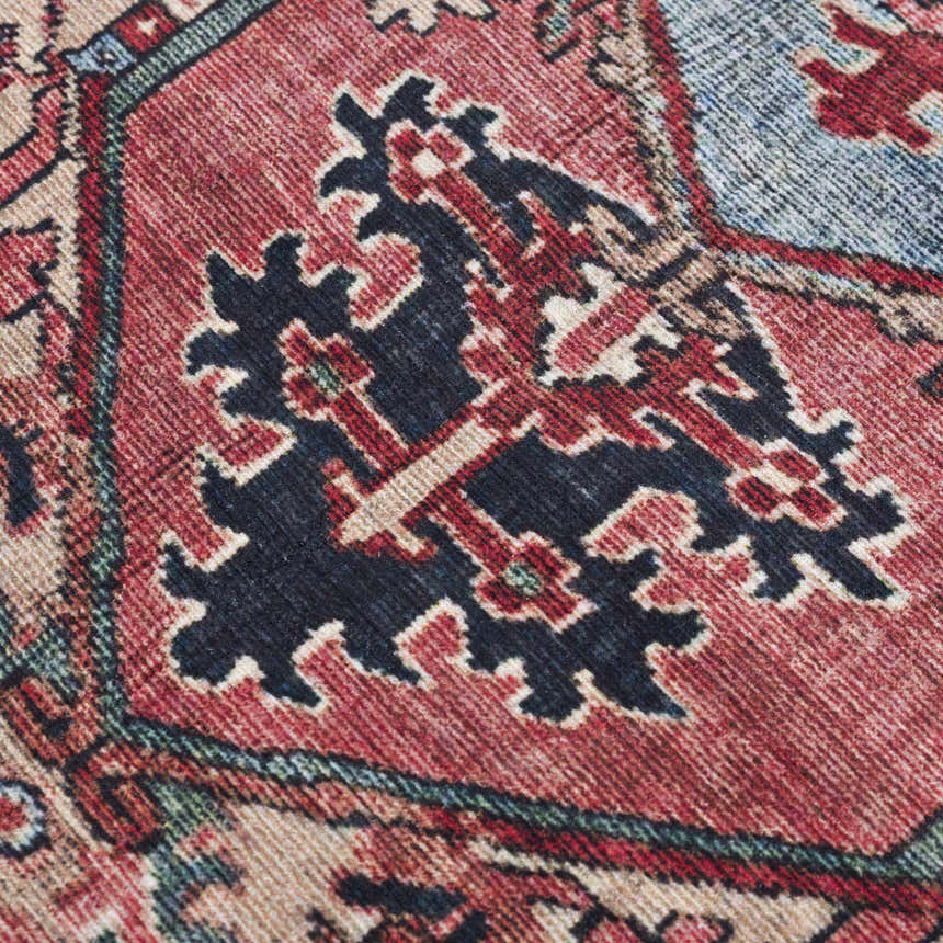 Close up of the Neyland Area Rug, featuring a traditional design in red, navy, beige, and blue. Texture