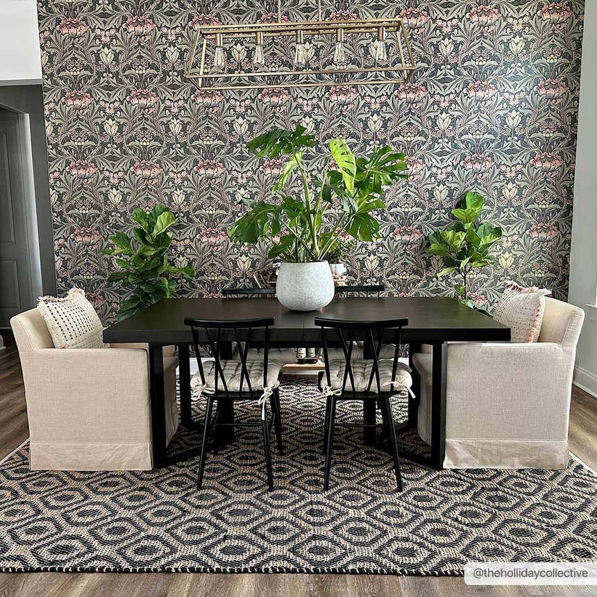Dining room with dark floral wallpaper and Isaye Charcoal Area Rug. Neutral chairs flank a black table with plants. Roomscene-Rectangle