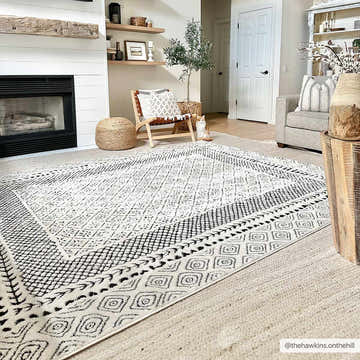 Living room scene with a black and ivory Julio Area Rug, fireplace, chair, and neutral decor. Roomscene-Rectangle