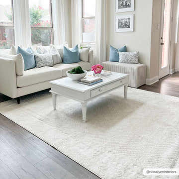 Living room scene with a soft, textured Julio Ivory Area Rug, white sofa, and blue accent pillows. Bright, airy, and inviting. Roomscene-Rectangle