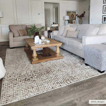 Living room scene with a beige sofa, wood coffee table, and the Keita Cream & Brown Area Rug. Roomscene-Rectangle