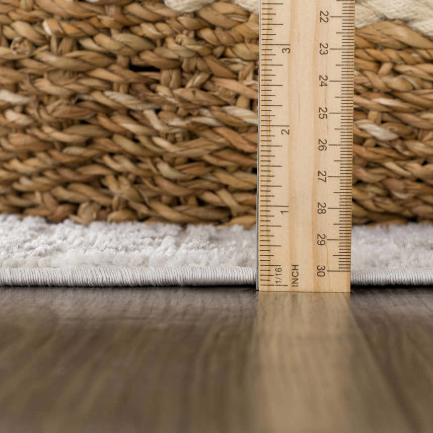 Close-up of the plush pile height of the gray and light gray Basia Area Rug, with a ruler for scale. Pile