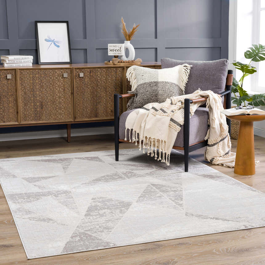 Living room scene with gray Basia Area Rug, geometric pattern. Gray walls, wood furniture, and a cozy chair create a modern look. Roomscene-Rectangle