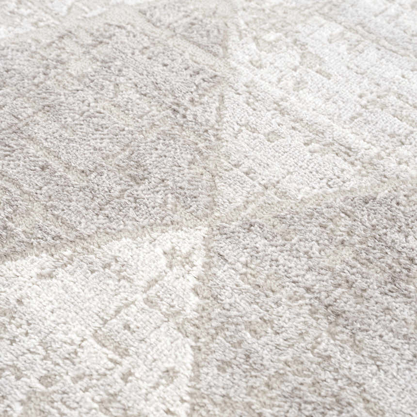 Close-up of the Basia Area Rug, a gray and light gray rug with a subtle geometric pattern and soft, textured pile. Texture