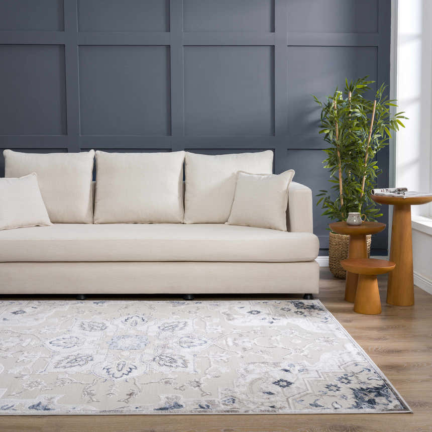 Living room scene with a Calum Blue & Gray Area Rug, neutral sofa, blue accent wall, and wooden side tables. Roomscene-Rectangle
