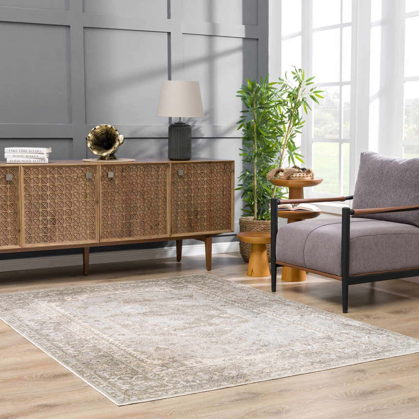 Living room scene with tan Gael Boutique Washable Rug, gray walls, wood cabinet, chair, and bright natural light. Roomscene-Rectangle