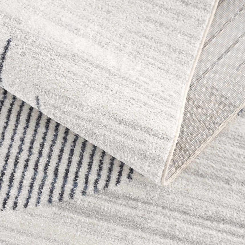 Close-up of the Thad Medium Gray Washable Area Rug showing its geometric pattern, soft texture, and durable backing. Fold