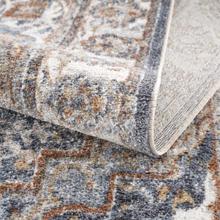 Close-up of the Aurum Blue & Beige Washable Area Rug showing its traditional pattern, texture, and gray, blue, and brown colors. Fold