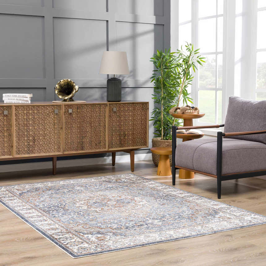 Living room with Aurum Blue & Beige Washable Area Rug, wood cabinet, gray chair, and natural light. Farmhouse style. Roomscene-Rectangle
