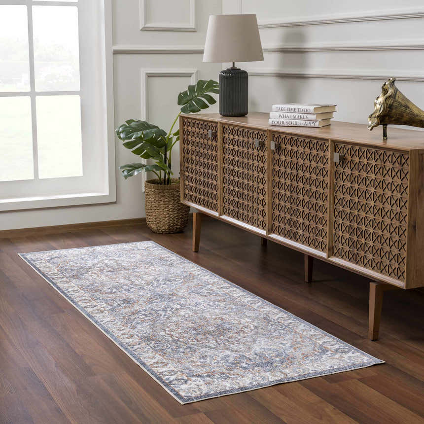Living room scene with Aurum Blue & Beige Washable Area Rug runner, wood floors, and a decorative wood cabinet. Roomscene-Runner