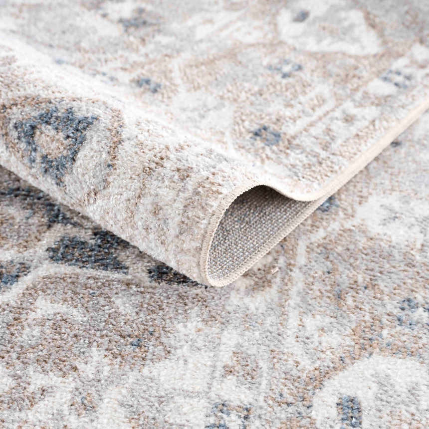 Close-up of the Dobry Boutique Washable Rug showing the blue, tan, and off-white vintage pattern and soft texture. Fold