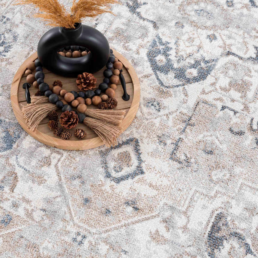 Close-up of the Dobry Boutique Washable Rug. Features a blue, off-white, and tan vintage pattern. Styleshot