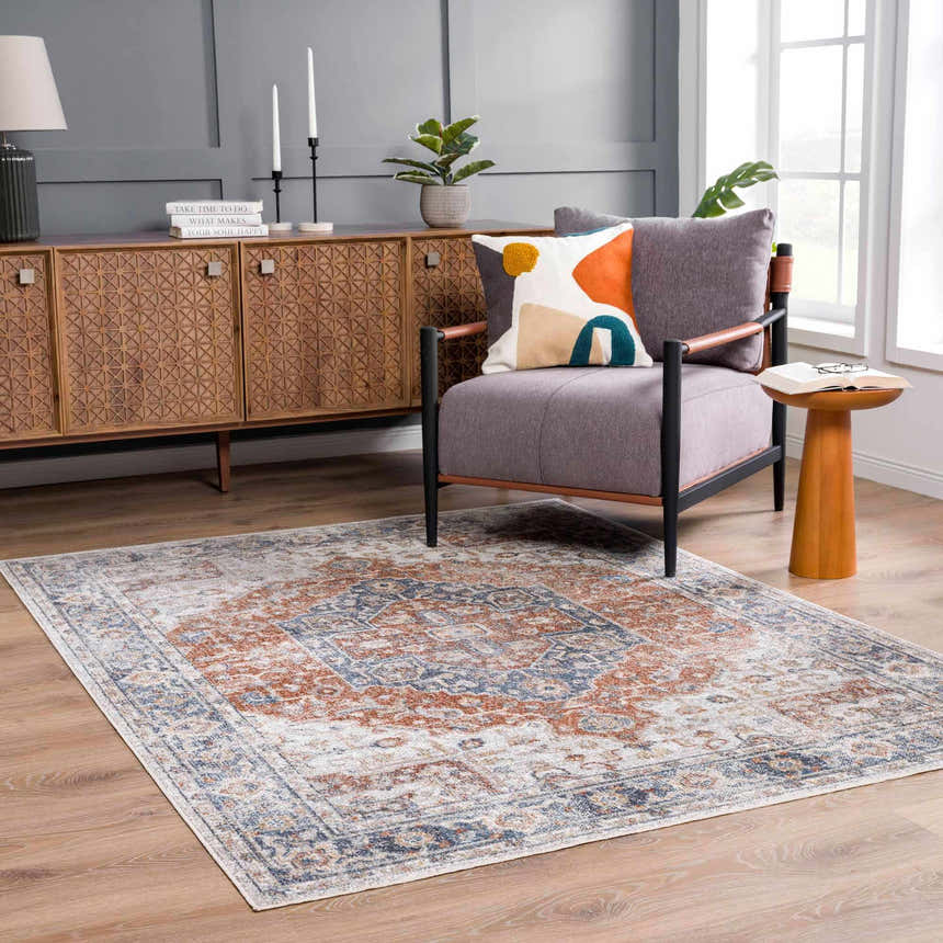 Living room scene with Akram Gray & Orange Washable Area Rug, gray chair, wood accents, and modern decor. Roomscene-Rectangle