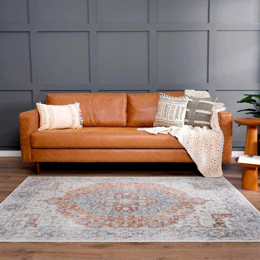 Living room scene with a brown leather sofa and Akram Gray & Orange Washable Area Rug adding a vintage, traditional style. Roomscene-Rectangle