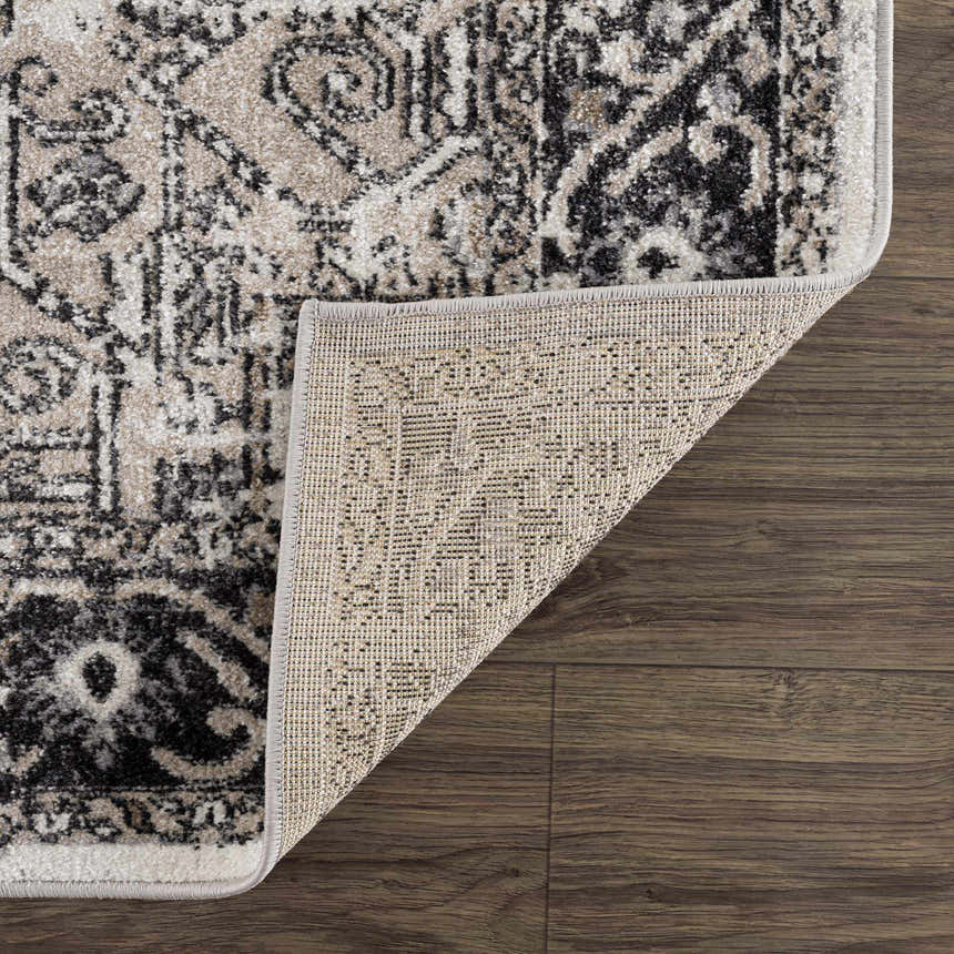Close-up of the Cabacungan Washable Area Rug showing its black, gray, and beige vintage-style pattern and woven texture. Fold