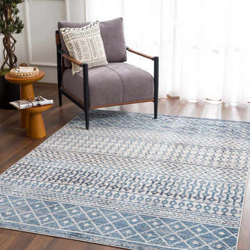 Living room scene with a blue and beige Southglenn Washable Area Rug, gray chair, and wood accents. Roomscene-Rectangle