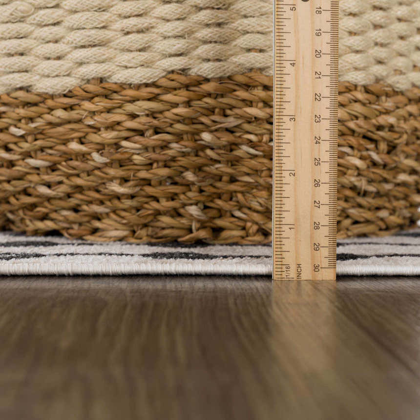 Close-up of the Joppatowne Washable Area Rug showing the pile height with a ruler. Black, cream, and gray geometric pattern. Pile