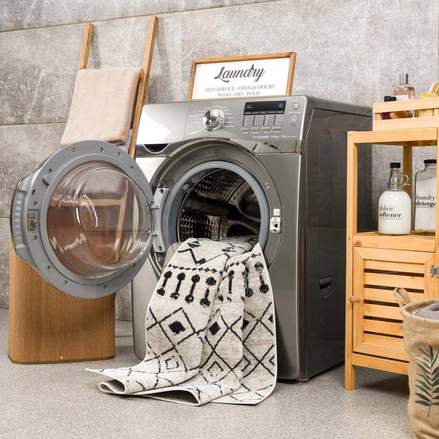 Laundry room scene with a Joppatowne Washable Area Rug partially inside a washing machine. Black and cream geometric pattern. Washing-Machine