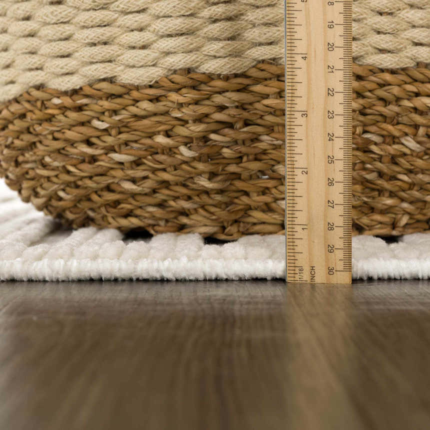Close-up of the plush, off-white pile height of the Deron White Washable 3D Rug with a ruler for scale. Pile