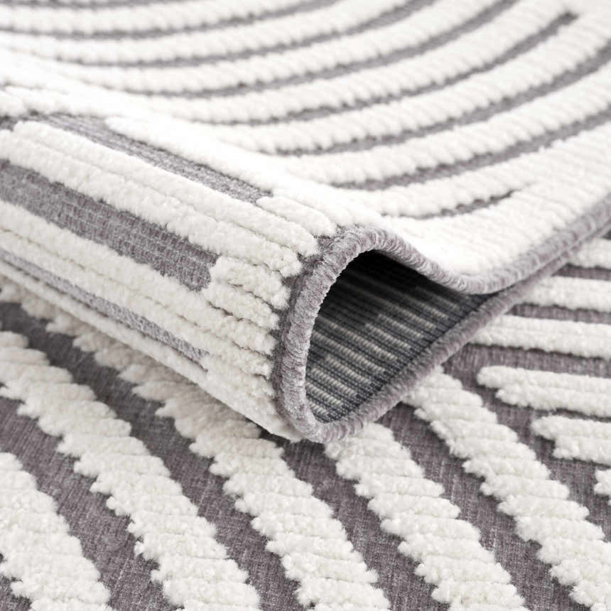 Close-up of the Deron Gray Rainbow Washable Rug showing gray and white geometric stripes and soft, textured pile. Fold