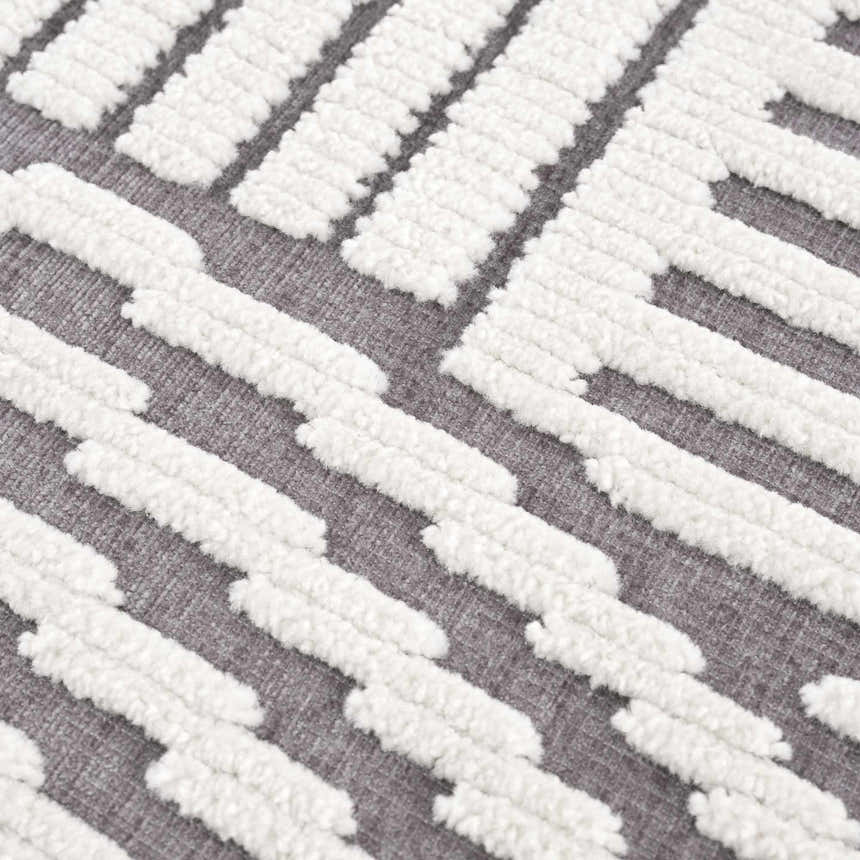 Close-up of the Deron Gray Rainbow Washable Rug, showing a geometric pattern in gray and textured white cotton. Texture