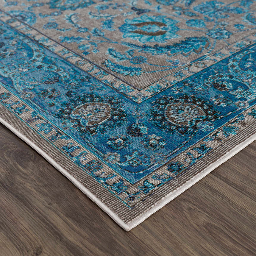 Close-up of the Mardina Turquoise Area Rug showing its beige and turquoise traditional vintage pattern and machine woven texture. Corner