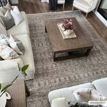 Living room scene with a Margaret Damask Sage Washable Area Rug, neutral sofas, and a dark wood coffee table. Roomscene-Rectangle