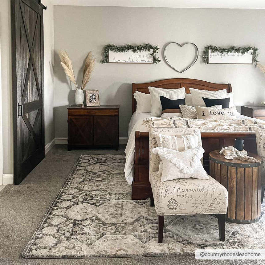 Bedroom scene with a beige and black Minoa Area Rug, wood furniture, and neutral decor. Roomscene-Rectangle