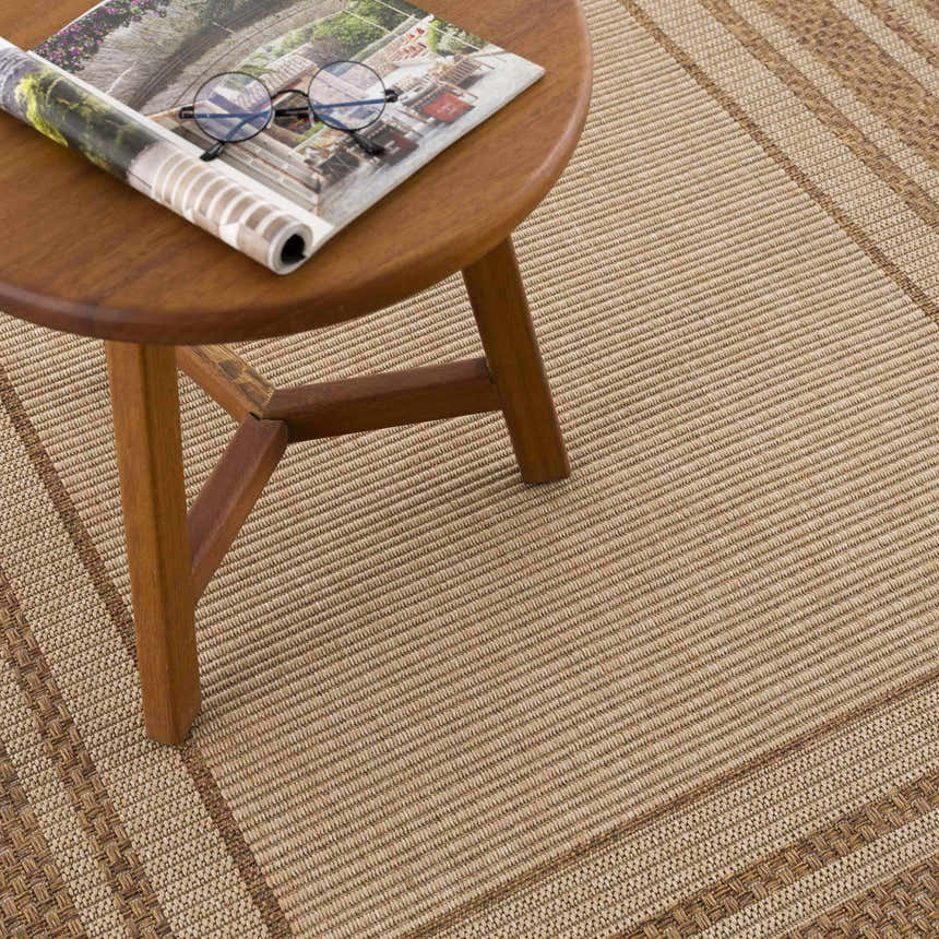 Close-up of the Isoko Bordered Faux Jute Rug in camel and brown, showing the texture and bordered design. Styleshot