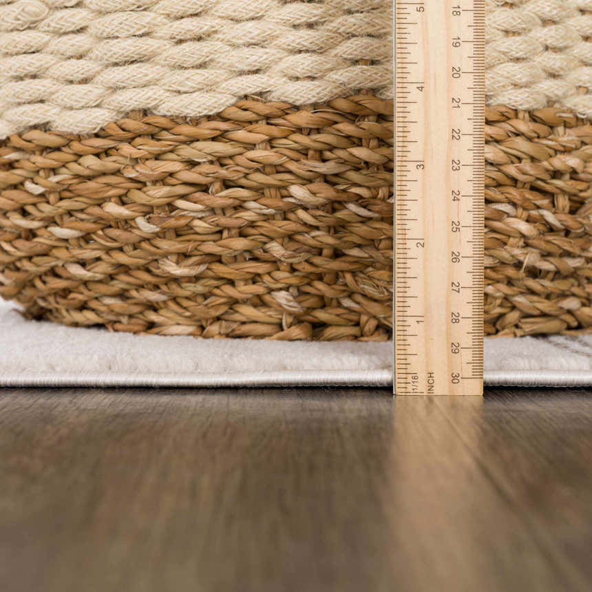 Close-up of Deja Cream & Charcoal Area Rug edge, showing cream color and pile height with a ruler for scale. Pile