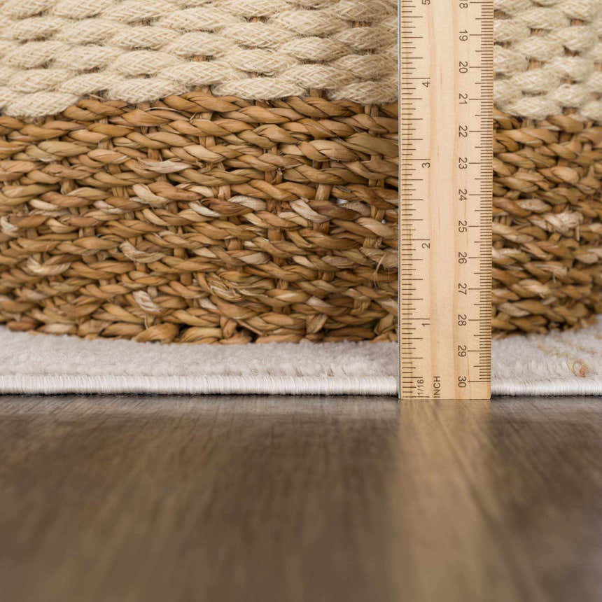 Close-up of the Deja Cream & Gold Area Rug showing texture and pile height with a ruler for scale. Pile