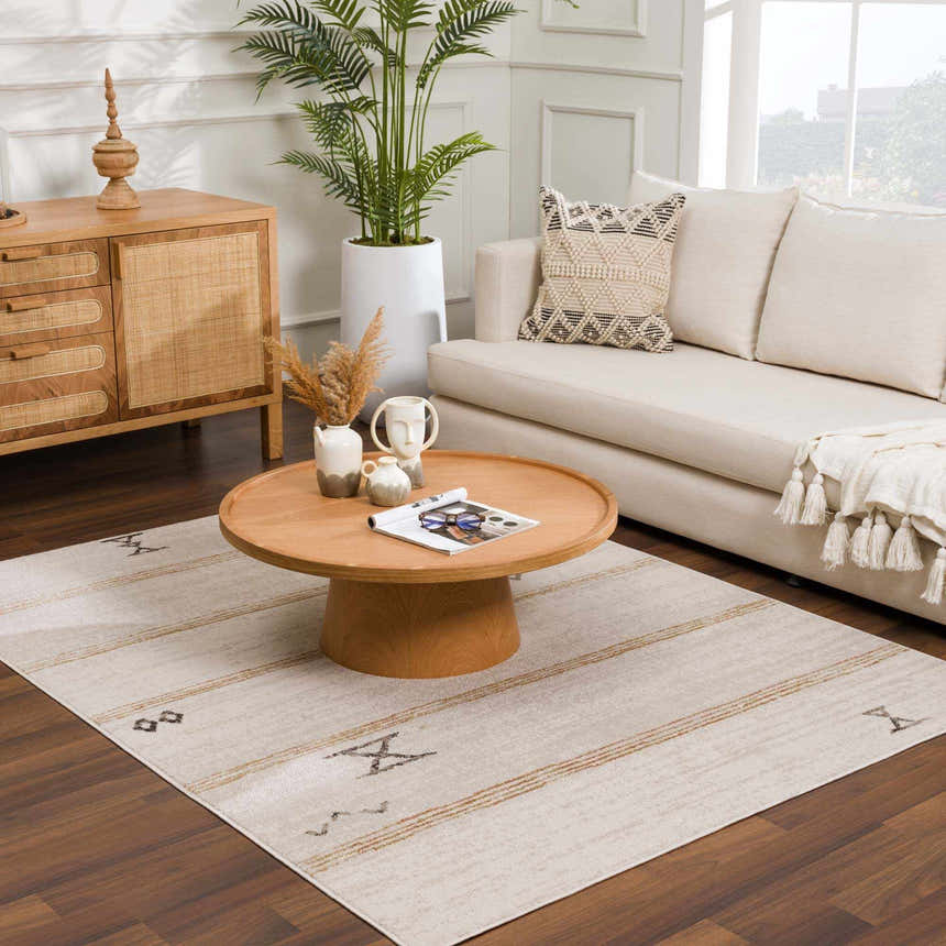 Living room scene with a Deja Cream & Gold Area Rug, light sofa, wood coffee table, and natural decor creating a cozy, bohemian vibe. Roomscene-Rectangle
