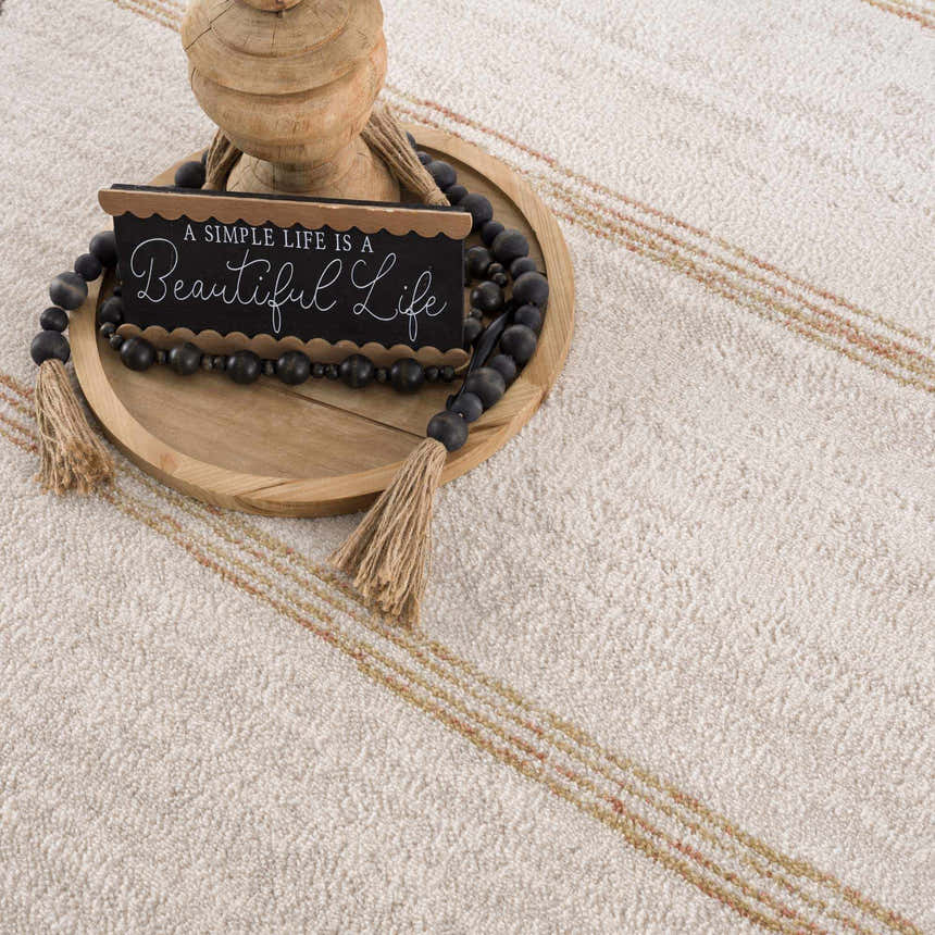 Close-up of Deja Cream & Gold Area Rug showing its textured weave and subtle gold and cream stripes. Styled with wood decor. Styleshot