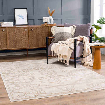 Living room scene with a Divya Cream & Gold Area Rug, wood cabinet, gray chair, and blue accent wall. Southwestern style. Roomscene-Rectangle