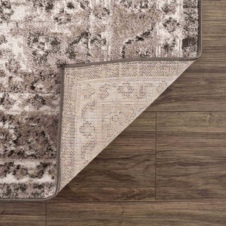 Close-up of the Albie Charcoal & Beige Area Rug showing its traditional pattern, woven texture, and backing on dark wood floor. Fold