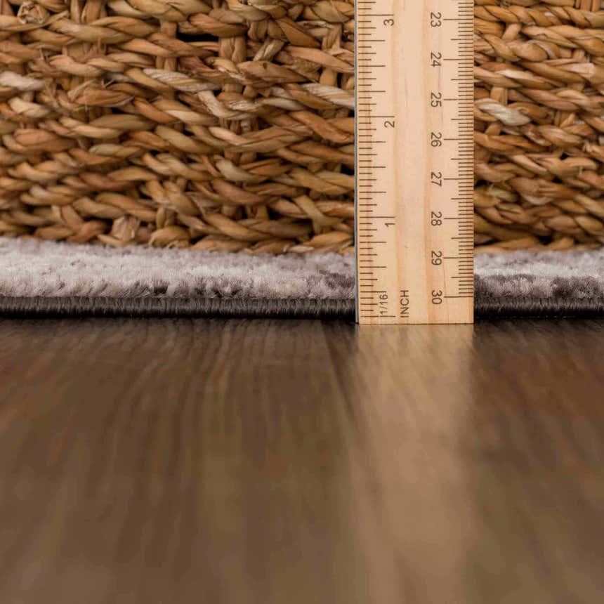 Close-up of the Albie Charcoal & Beige Area Rug pile height, measured with a ruler next to a woven basket. Pile