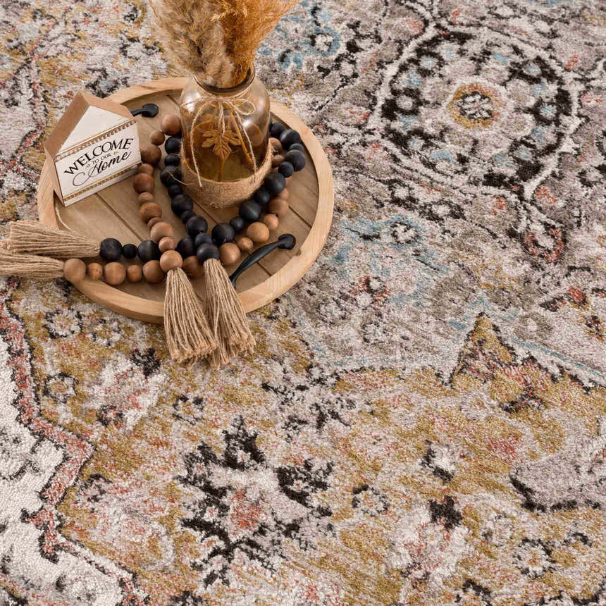 Close-up of the Albie Gold & Beige Area Rug showing its traditional vintage pattern and texture. Beige and gold tones. Styleshot