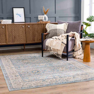 Living room scene with Anana Silver Blue & Beige Area Rug, gray chair, wood cabinet, and blue accent wall. Roomscene-Rectangle